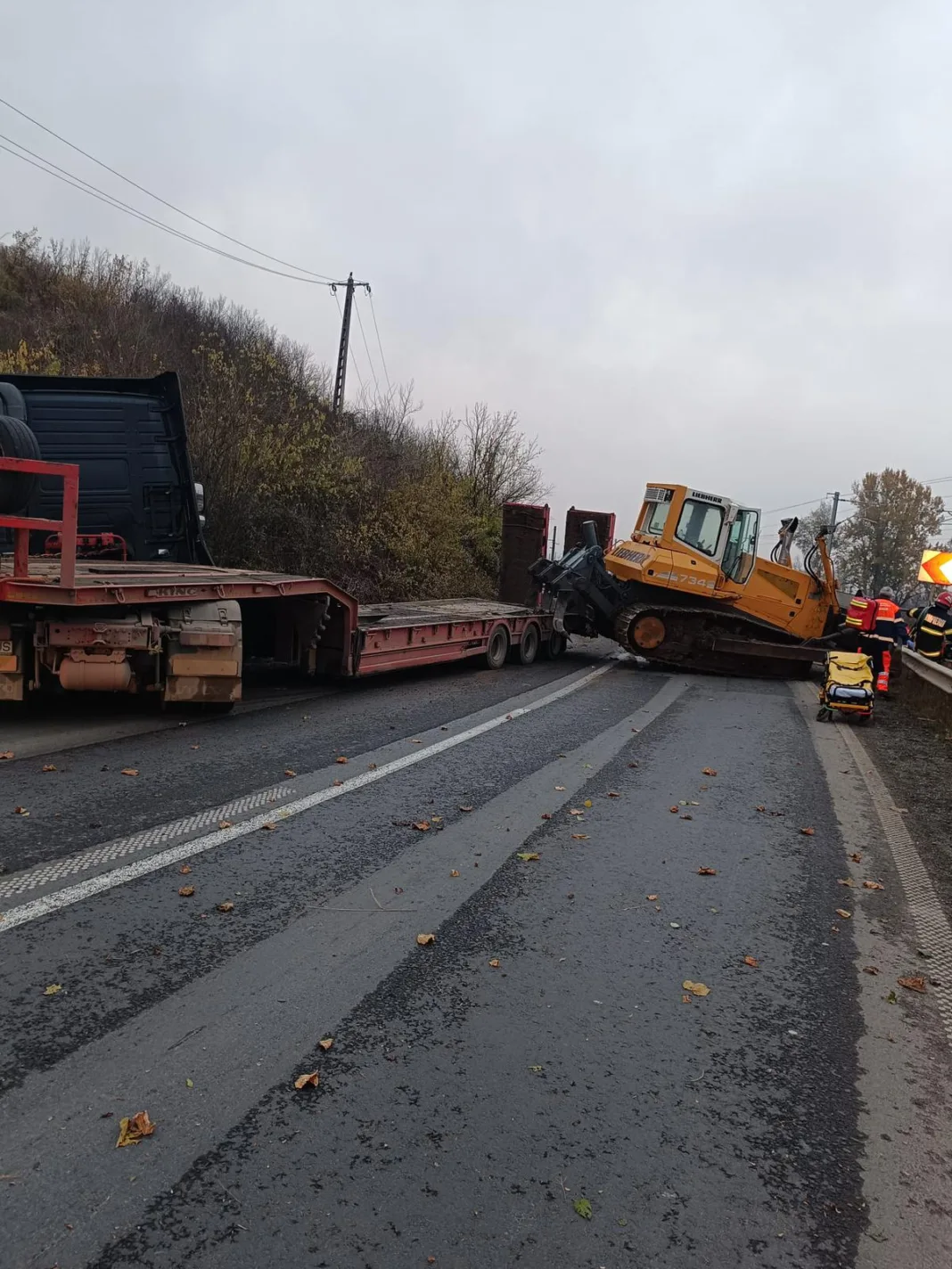 Două victime după ce un buldoexcavator a căzut de pe un trailer peste o maşină