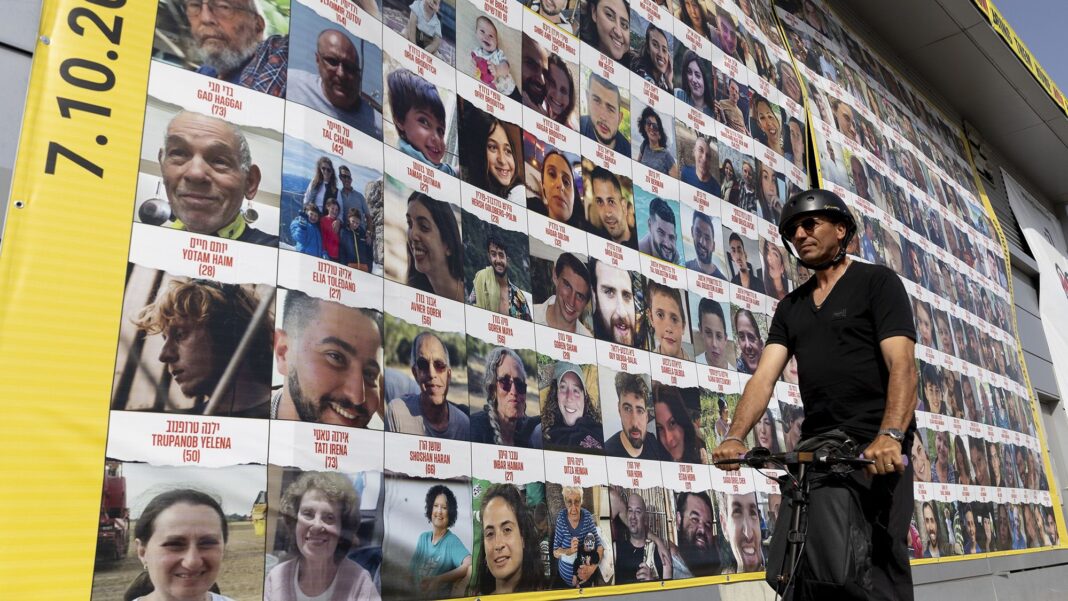 Un bărbat trece pe lângă o clădire care arată fotografii cu ostatici care au fost eliberați sau sunt încă ținuți în Gaza, pe 26 martie, în Tel Aviv, Israel (Amir Levy/Getty Images)