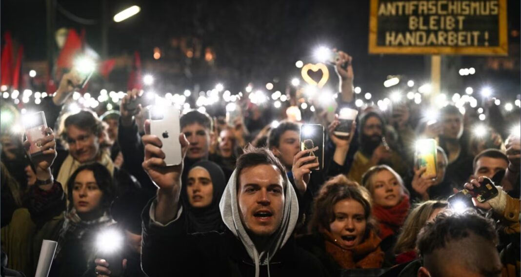 Oamenii își ridică telefoanele mobile în timp ce se adună în timpul unui protest împotriva mandatului Partidului Libertății de extremă-dreapta din Austria de a conduce un nou guvern, la Viena, Austria