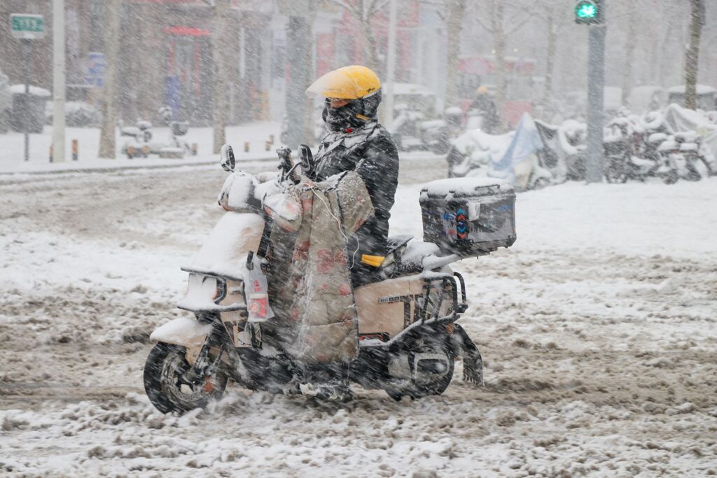 Un livrator în zăpadă pe 2 martie 2025 în Jinan, provincia Shandong din China